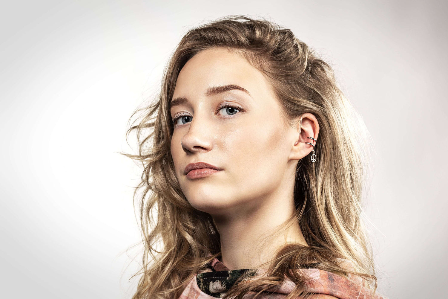 Woman wearing hearing aid retention cuff and Deafmetal earrings for personalization and style.