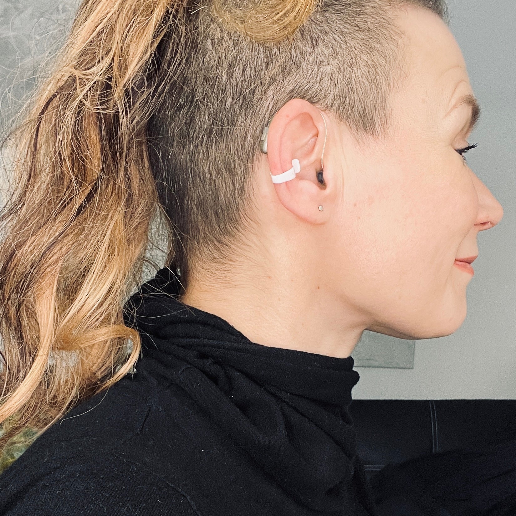 shows a woman wearing the white Deafmetal insurance clip