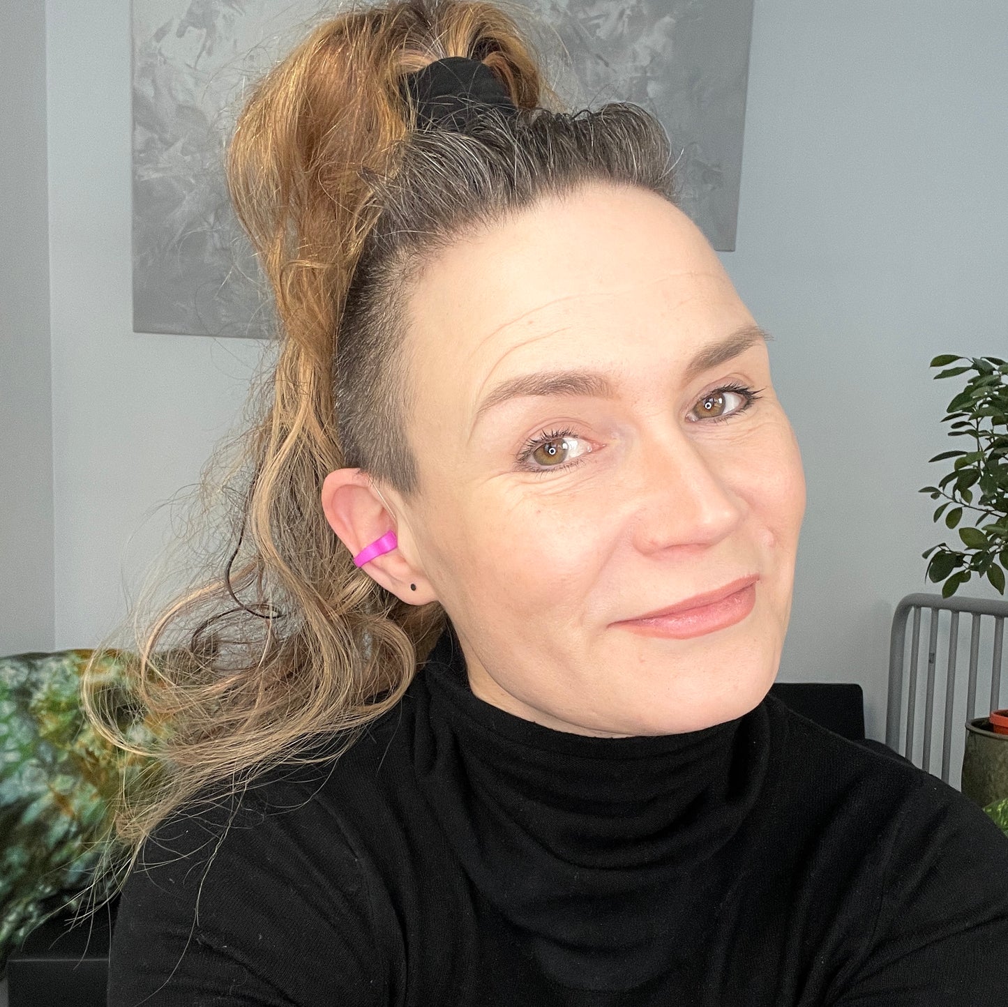 Woman wearing our pink Deafmetal insurance flexi clip to attach to her hearing aid