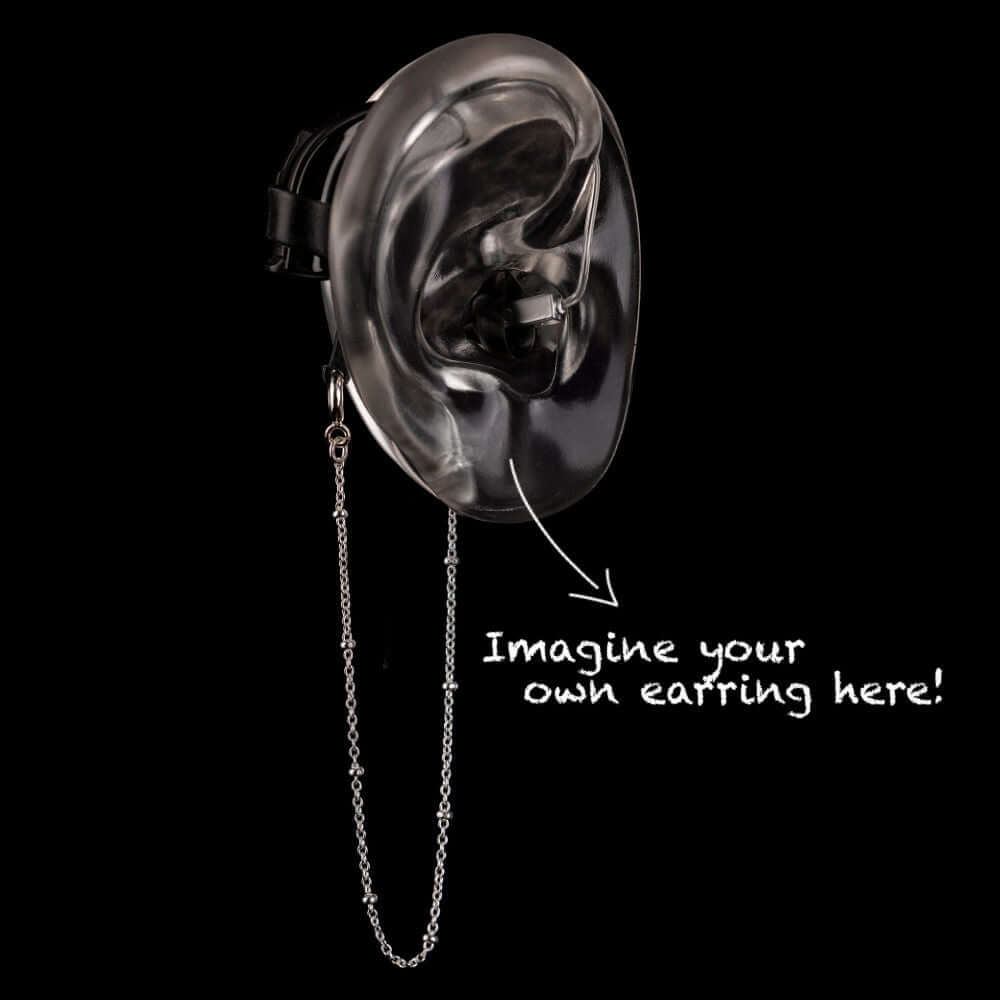 Beaded safety chain for hearing aids or cochlear implants in silver attached to a model ear with arrow pointing to earring spot.